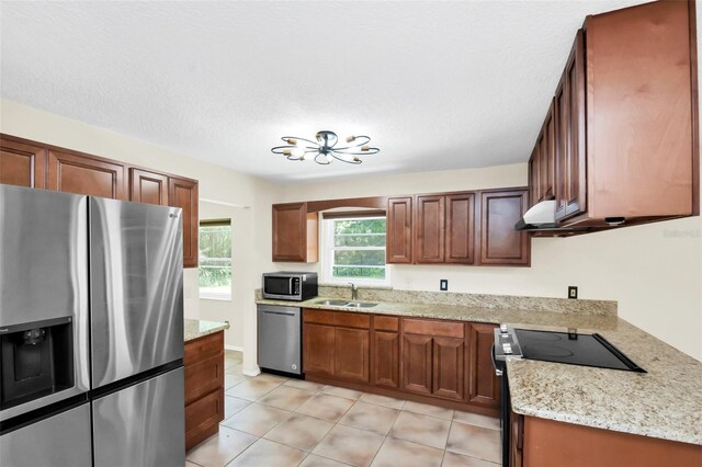 kitchen featuring light stone countertops, sink, stainless steel appliances, a textured ceiling, and light tile patterned floors