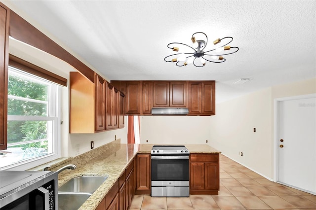 kitchen with kitchen peninsula, light stone counters, light tile patterned floors, stainless steel range oven, and a chandelier