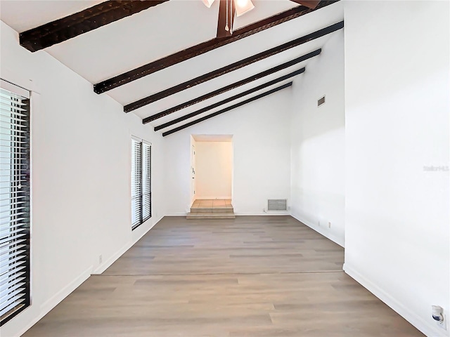 spare room featuring beam ceiling, hardwood / wood-style floors, and high vaulted ceiling