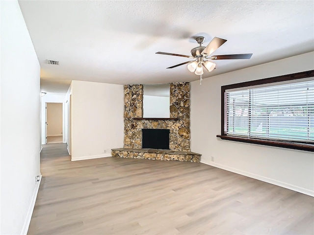 unfurnished living room featuring hardwood / wood-style flooring, ceiling fan, a fireplace, and a textured ceiling