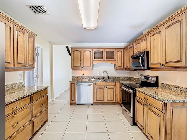 kitchen featuring light stone counters, sink, light tile patterned flooring, and appliances with stainless steel finishes