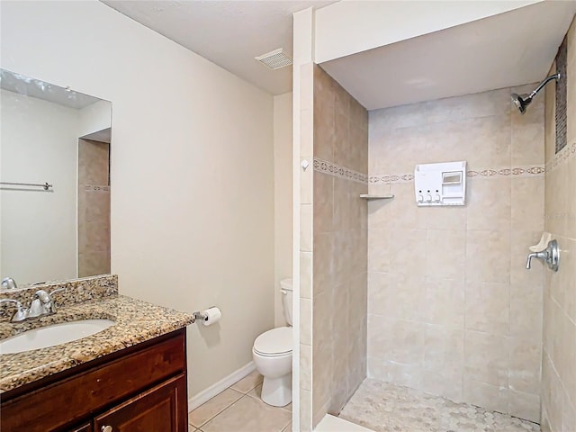 bathroom with tile patterned floors, vanity, a tile shower, and toilet