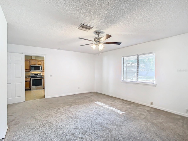 empty room featuring light carpet, ceiling fan, and a textured ceiling