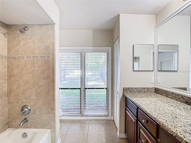 bathroom with tile patterned floors, vanity, a textured ceiling, and tiled shower / bath