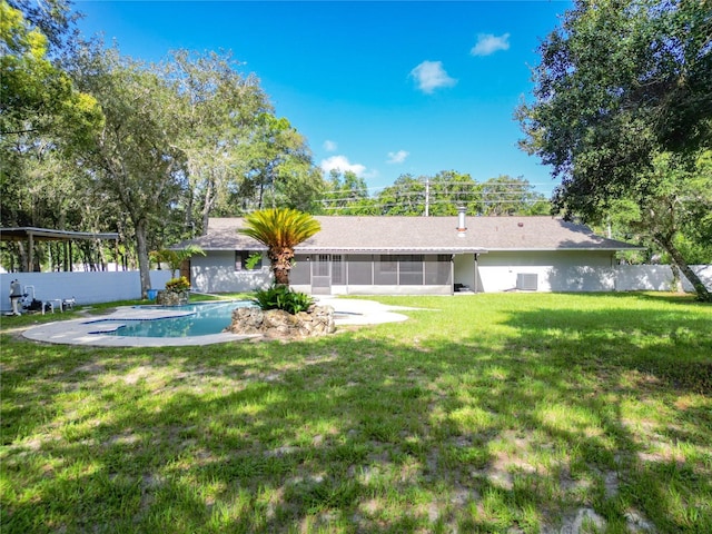 back of property with a yard, a fenced in pool, and a sunroom