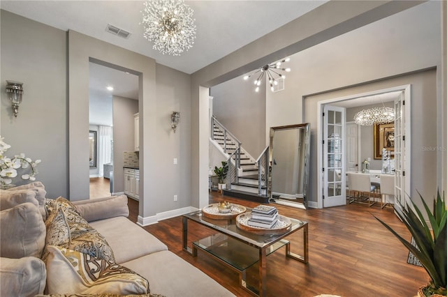 living area featuring a chandelier, wood finished floors, stairs, and baseboards