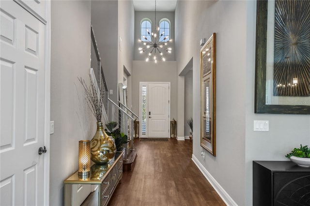 entryway featuring dark wood-style floors, a notable chandelier, stairway, a high ceiling, and baseboards