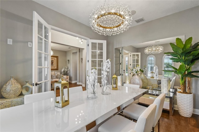 dining area with french doors, wood finished floors, visible vents, and a notable chandelier