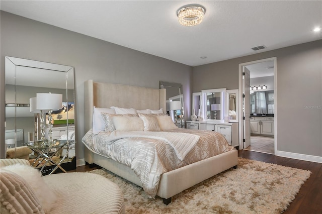 bedroom with baseboards, visible vents, wood finished floors, and ensuite bathroom