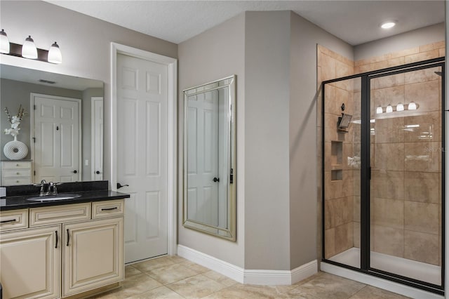 bathroom featuring a stall shower, tile patterned flooring, baseboards, and vanity