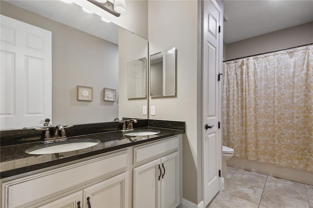 bathroom with toilet, double vanity, a sink, and tile patterned floors