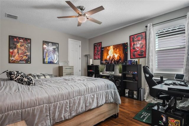 bedroom with ceiling fan, a textured ceiling, visible vents, and wood finished floors