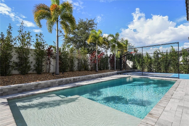 view of swimming pool featuring a fenced backyard and basketball hoop