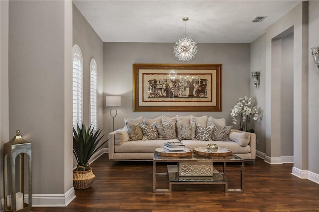 living room with visible vents, a notable chandelier, baseboards, and wood finished floors