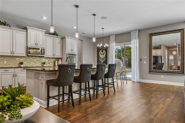 kitchen featuring white cabinets, decorative backsplash, dark countertops, dark wood-style floors, and stainless steel appliances