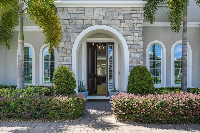 doorway to property with stone siding and stucco siding