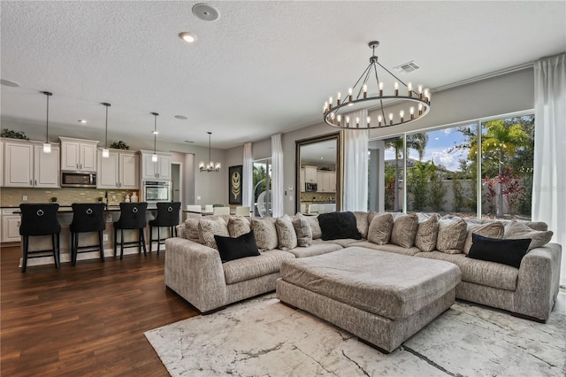 living room featuring a chandelier, visible vents, a textured ceiling, and wood finished floors