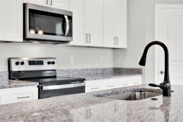 kitchen featuring white cabinets, light stone counters, appliances with stainless steel finishes, and sink