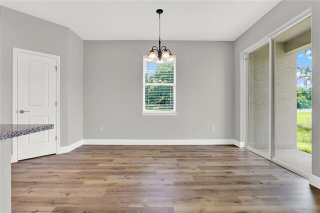 unfurnished dining area featuring hardwood / wood-style floors, an inviting chandelier, and a wealth of natural light