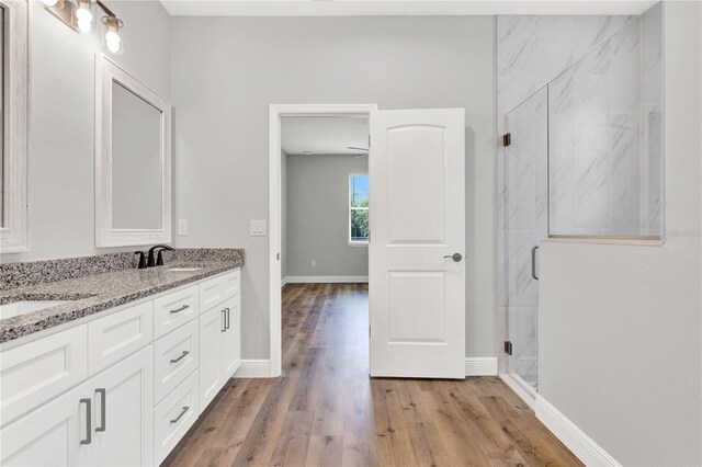 bathroom featuring an enclosed shower, wood-type flooring, and dual bowl vanity