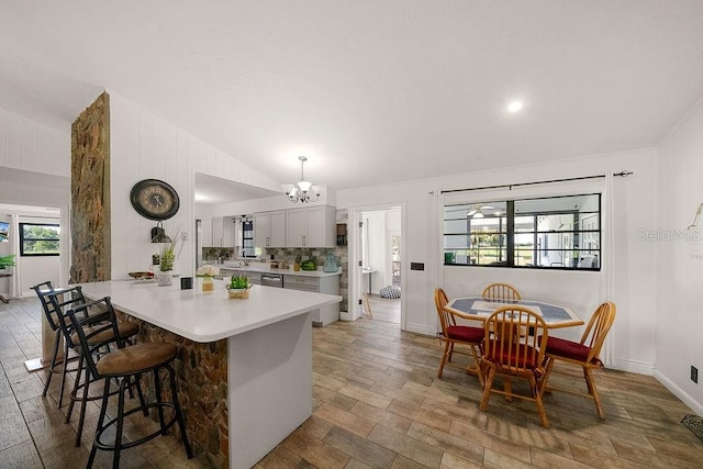 kitchen with pendant lighting, stainless steel dishwasher, a wealth of natural light, and vaulted ceiling