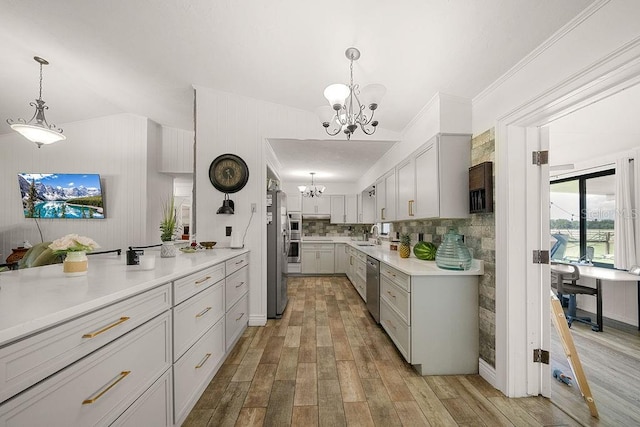 kitchen with appliances with stainless steel finishes, gray cabinetry, hanging light fixtures, a notable chandelier, and light hardwood / wood-style flooring