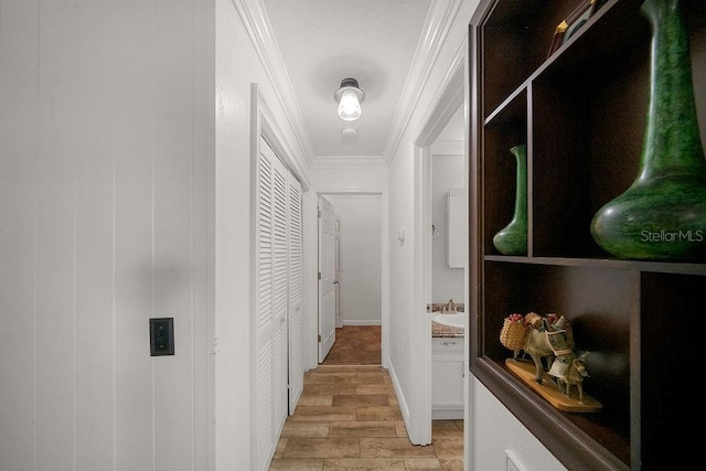 hall with light wood-type flooring, crown molding, and sink