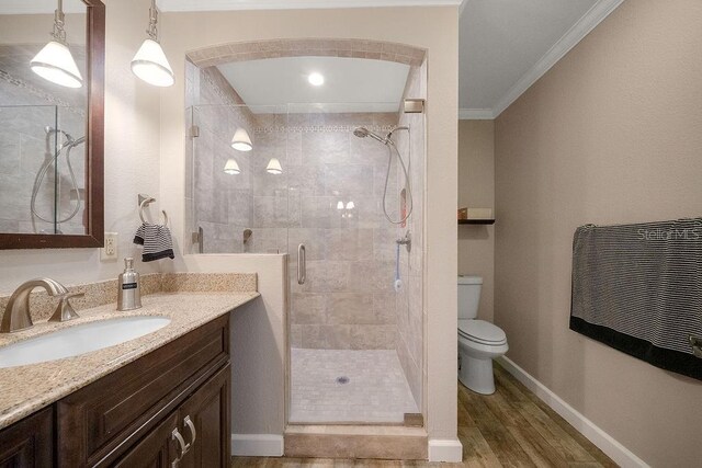 bathroom with hardwood / wood-style floors, vanity, toilet, walk in shower, and ornamental molding