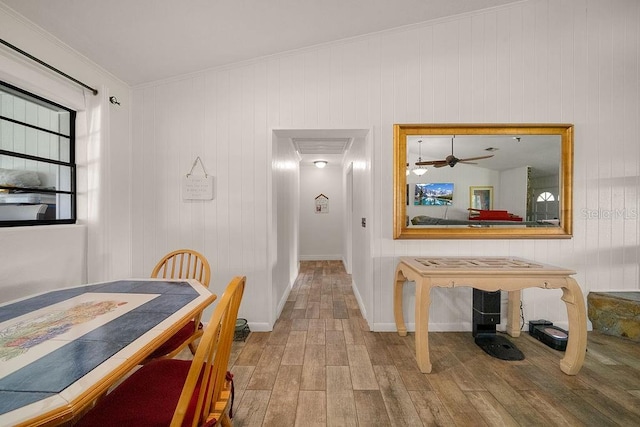 corridor with wood walls, light hardwood / wood-style floors, and ornamental molding