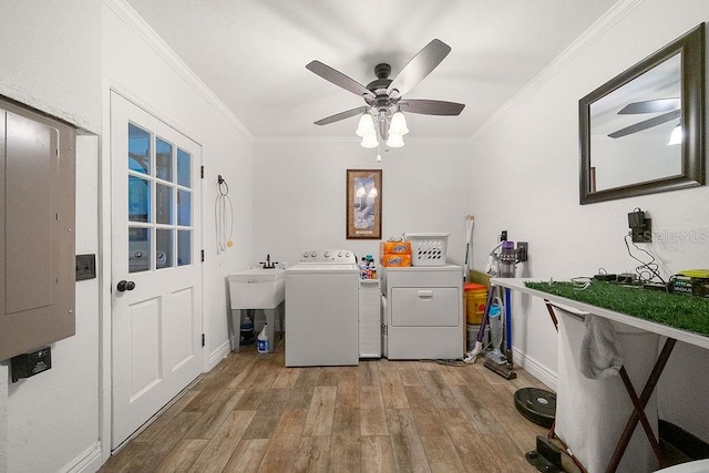 clothes washing area with separate washer and dryer, light hardwood / wood-style floors, sink, ornamental molding, and electric panel