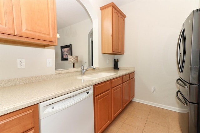 kitchen featuring sink, light tile patterned floors, stainless steel fridge, and white dishwasher