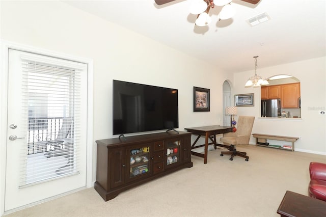 living room with ceiling fan with notable chandelier and light colored carpet