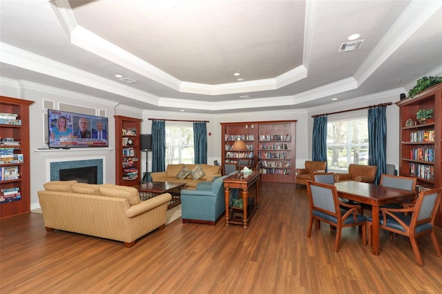 living room with a wealth of natural light, crown molding, a raised ceiling, and hardwood / wood-style floors