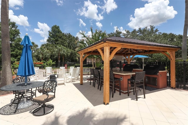 view of patio / terrace with a gazebo, a bar, and area for grilling