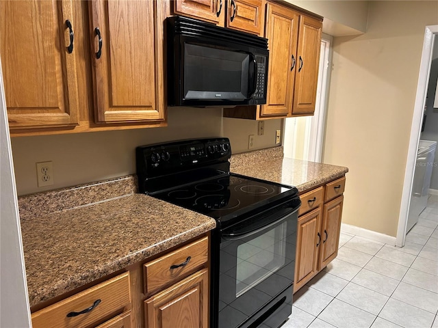 kitchen featuring black appliances, light tile patterned floors, and dark stone countertops