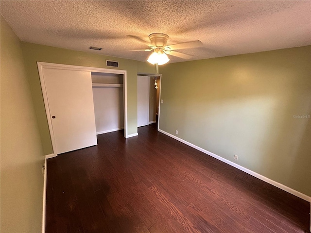 unfurnished bedroom featuring ceiling fan, a closet, dark hardwood / wood-style floors, and a textured ceiling