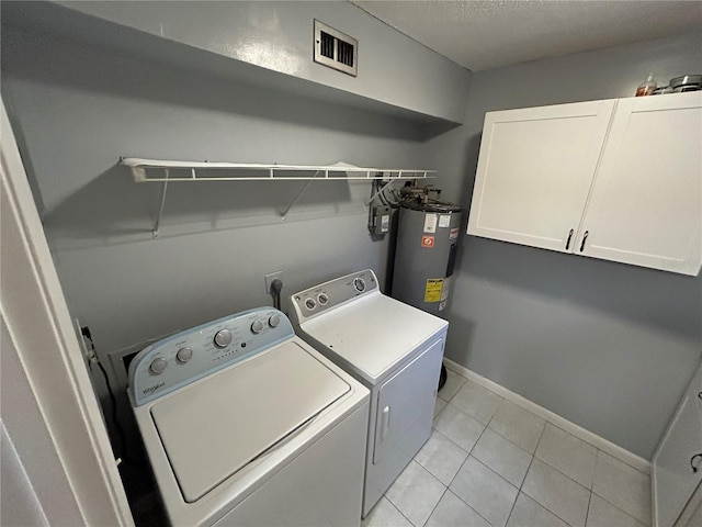 laundry room featuring electric water heater, independent washer and dryer, a textured ceiling, light tile patterned floors, and cabinets