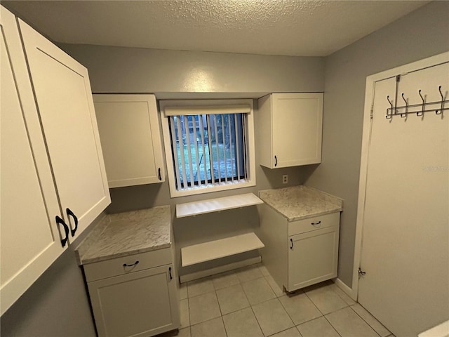 kitchen featuring light tile patterned flooring, white cabinetry, and a textured ceiling