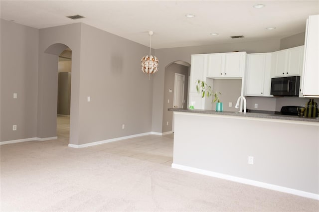 kitchen featuring white cabinets, sink, decorative light fixtures, light colored carpet, and range