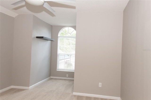 empty room featuring ceiling fan, lofted ceiling, and light carpet