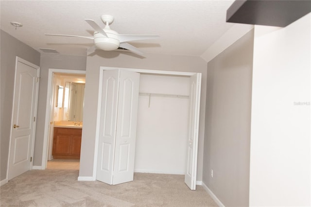 unfurnished bedroom with light carpet, connected bathroom, a closet, and ceiling fan