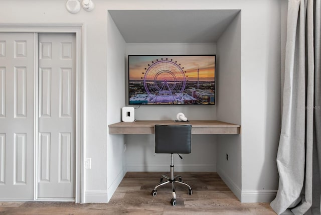 home office featuring wood finished floors, built in desk, and baseboards