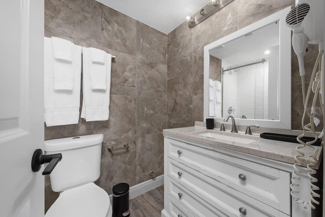 bathroom featuring vanity, tile walls, toilet, and wood finished floors