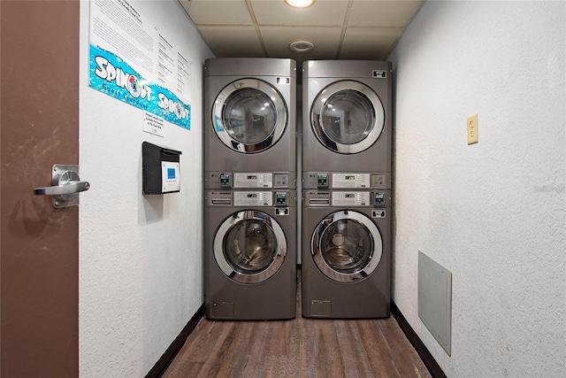 laundry room with stacked washer / drying machine and dark wood-type flooring