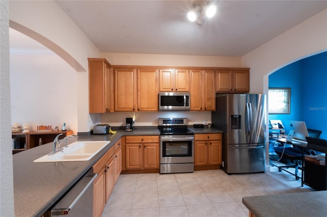 kitchen featuring stainless steel appliances, sink, and light tile patterned floors