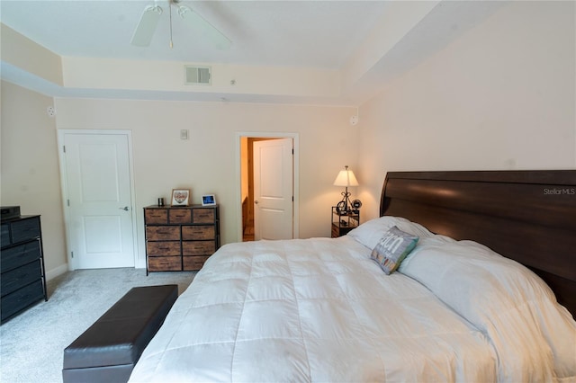 carpeted bedroom with ceiling fan and a raised ceiling