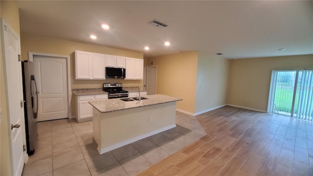 kitchen featuring a center island with sink, sink, white cabinetry, light stone countertops, and appliances with stainless steel finishes