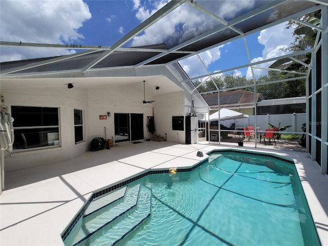 view of swimming pool featuring glass enclosure, a patio area, and ceiling fan