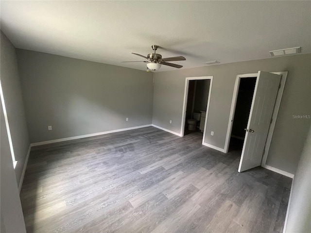 unfurnished bedroom with ensuite bath, dark hardwood / wood-style floors, and ceiling fan