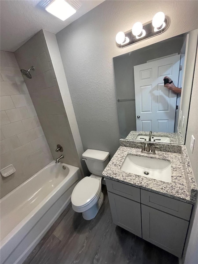 full bathroom featuring vanity, hardwood / wood-style flooring, toilet, and tiled shower / bath